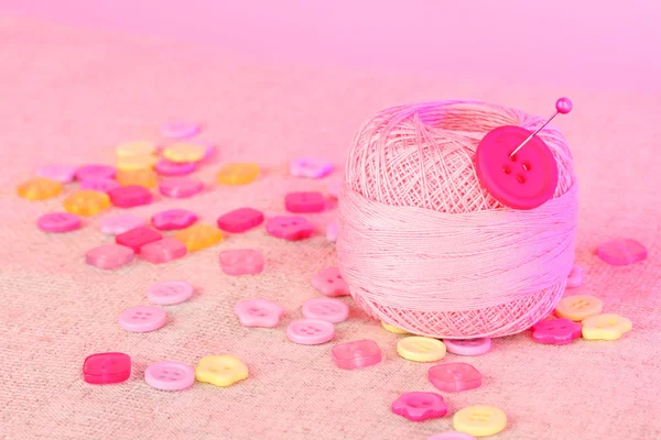 Beautiful buttons and a ball of yarn on a pink background — Stock Photo, Image