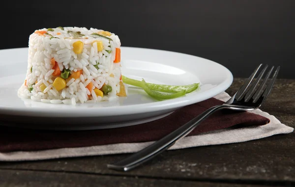 Delicious risotto with vegetables on wooden table, on grey background — Stock Photo, Image