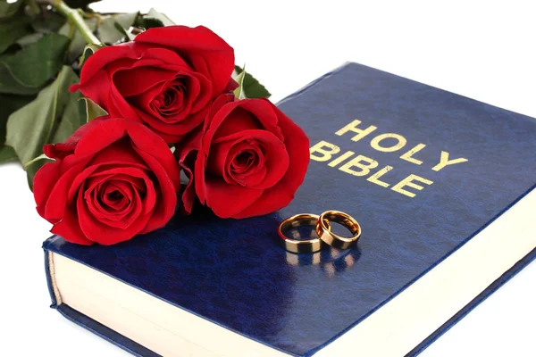 Wedding rings with roses on bible isolated on white — Stock Photo, Image