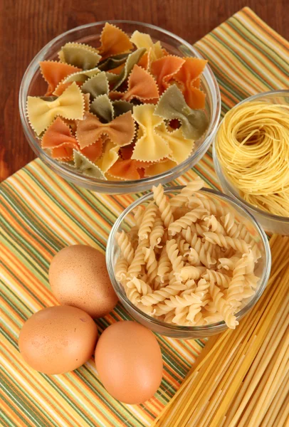 Verschillende soorten pasta op gestreepte tafellaken — Stockfoto