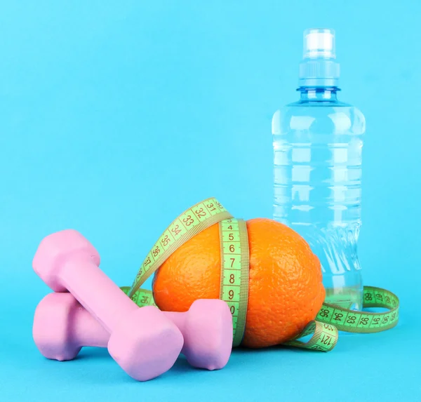 Πορτοκαλί με μέτρηση ταινία, αλτήρες και μπουκάλι νερό, σε φόντο χρώμα — Φωτογραφία Αρχείου
