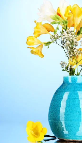 Mooi boeket van fresia's in vaas op blauwe achtergrond — Stockfoto