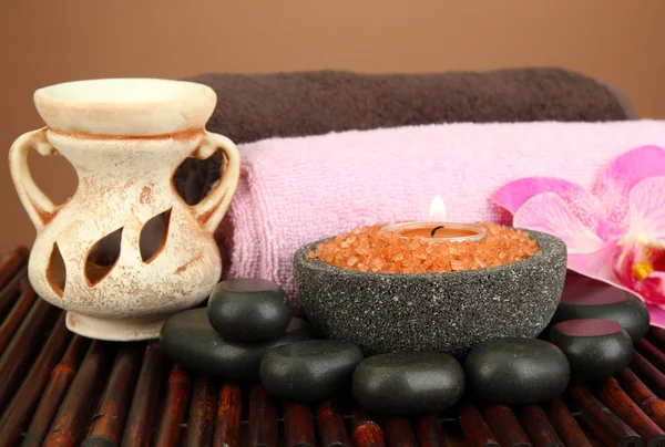 Candle in stone bowl with marine salt, on bamboo mat, on brown background — Stock Photo, Image