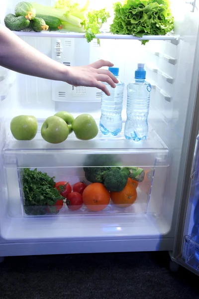 Рука женщины тянется за едой из холодильника, закрывается — стоковое фото