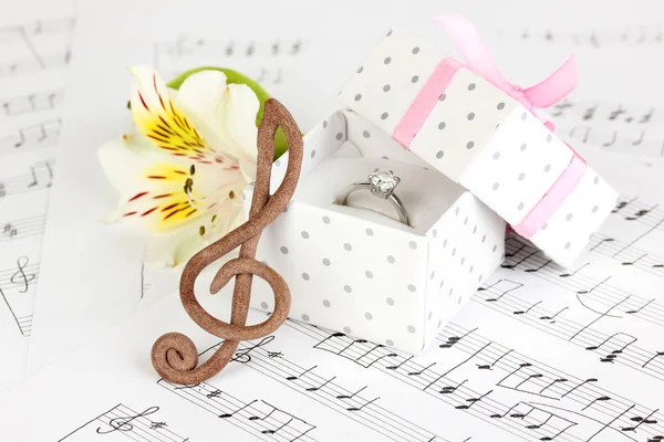 Chiave di violino, fiore e scatola con anello nuziale su sfondo musicale — Foto Stock