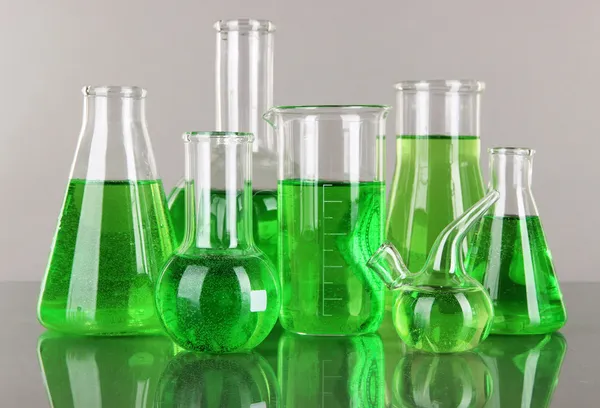 灰色の背景に緑色の液体と試験管 — ストック写真