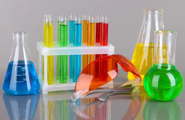 Test-buizen met kleurrijke vloeistoffen op grijze achtergrond — Stockfoto
