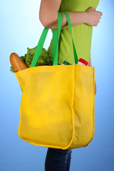 Meisje met boodschappentas op blauwe achtergrond — Stockfoto