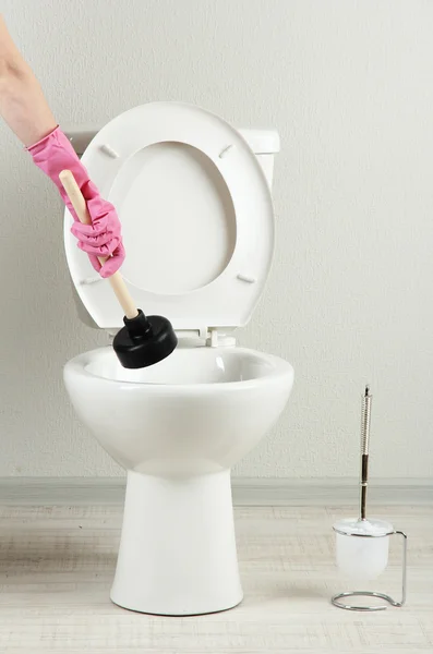 女性は、バスルームの便器の詰まりを取るにプランジャーを使用してください。 — ストック写真