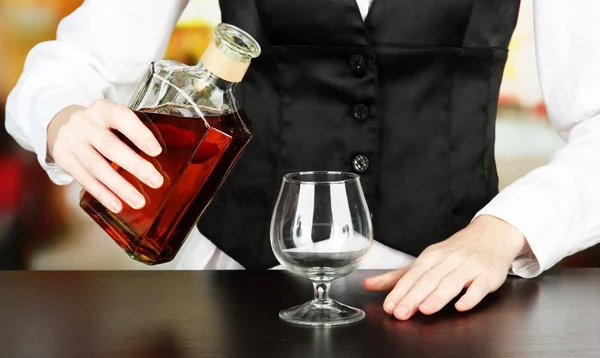 コニャック グラス、明るい背景上に注ぐ飲み物のボトルとバーマン手 — ストック写真
