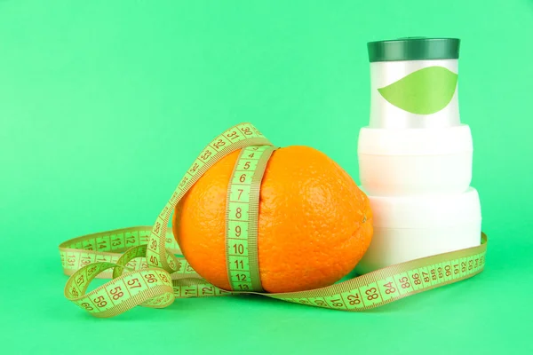 Naranja con cinta métrica y crema corporal, sobre fondo de color —  Fotos de Stock