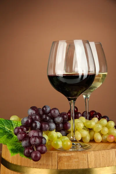 Glasses of red and white wine, grape on wooden barrel, on color background — Stock Photo, Image