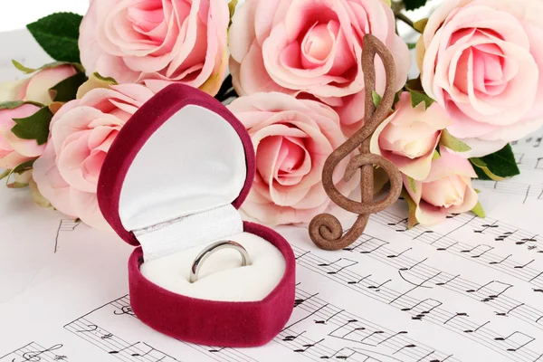 Treble clef, roses and box holding wedding ring on musical background — Stock Photo, Image