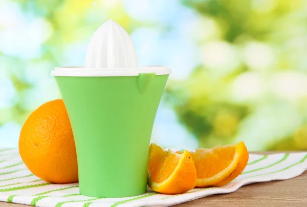 Citrus press and ripe oranges on brown wooden table — Stock Photo, Image