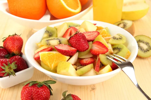 La ensalada útil de frutas frescas y las bayas en la escudilla a la mesa de madera el primer plano — Foto de Stock