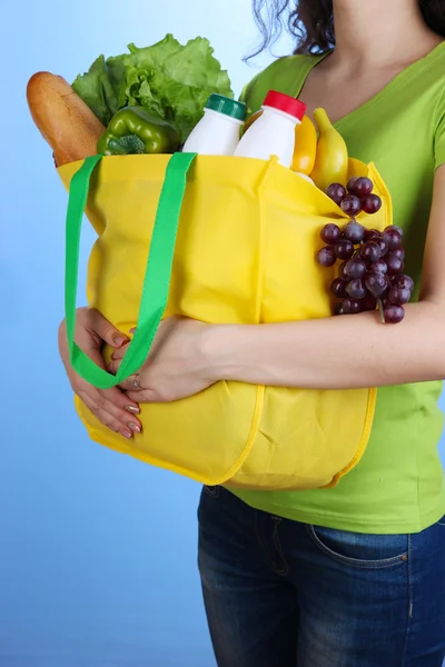 Meisje met boodschappentas op blauwe achtergrond — Stockfoto