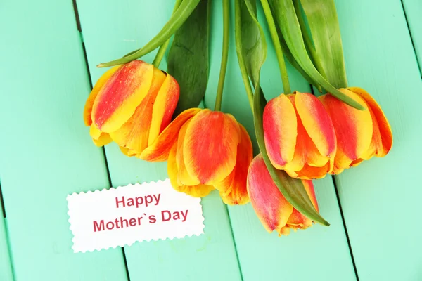 Krásné oranžové tulipány na barevné dřevěné pozadí — Stock fotografie