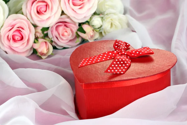 Beautiful gift on flowers background — Stock Photo, Image