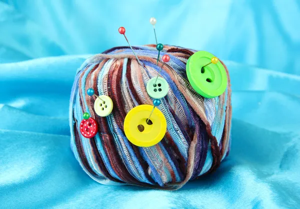 Botões coloridos e bolas de lã multicoloridas, em fundo de tecido de cor — Fotografia de Stock
