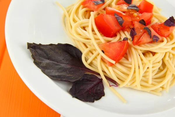 Spaghetti mit Tomaten und Basilikumblättern auf Holzgrund — Stockfoto