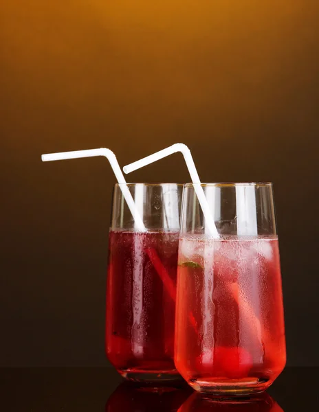 Due cocktail di ciliegie con ghiaccio su sfondo arancione scuro — Foto Stock