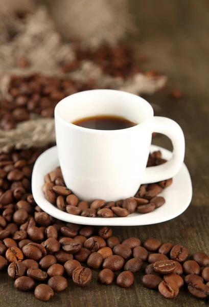 Чашка кофе и кофейных зерен на деревянном фоне Стоковое Фото