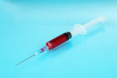 mavi zemin üzerine kan dolu plastik tek kullanımlık şırınga