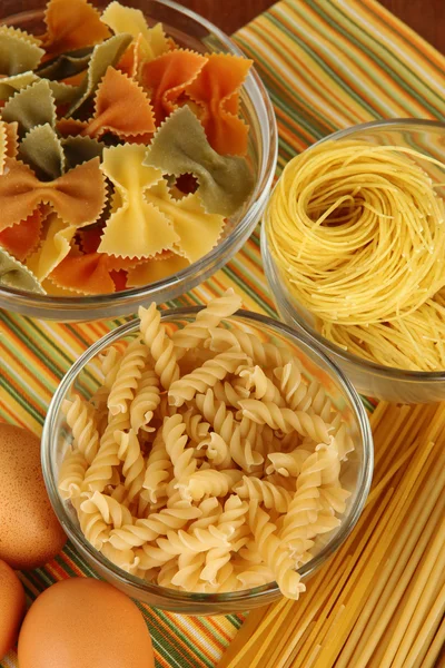 Verschillende soorten pasta op gestreepte tafellaken — Stockfoto