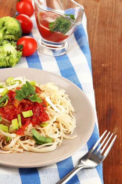 Smaczne spaghetti z sosem i warzywami na tabliczce na drewniany stół szczegół — Zdjęcie stockowe