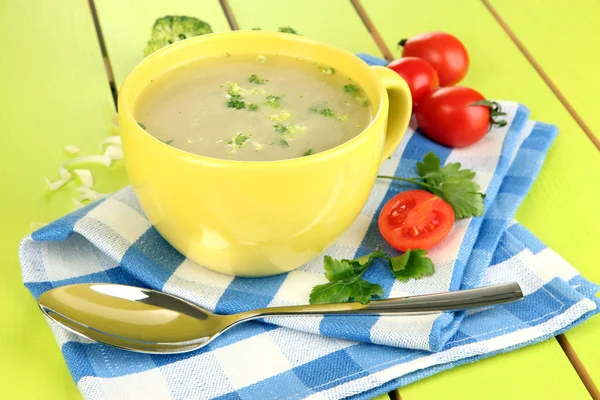 Диетический суп с овощами в чашке на зеленом деревянном столе крупным планом — стоковое фото