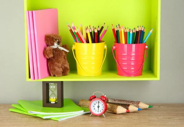 Lápis coloridos em pails na prateleira no fundo bege — Fotografia de Stock