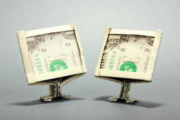 Dollars folded into computer monitors on grey background — Stock Photo, Image