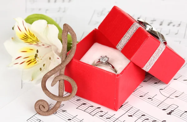 Fenda aguda, flor e caixa segurando anel de casamento no fundo musical — Fotografia de Stock