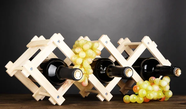 Bottles of wine placed on wooden stand on grey background — Stock Photo, Image