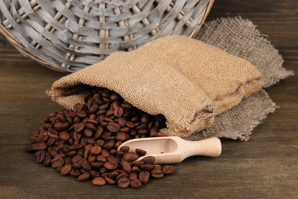 Grãos de café em saco no fundo de madeira — Fotografia de Stock