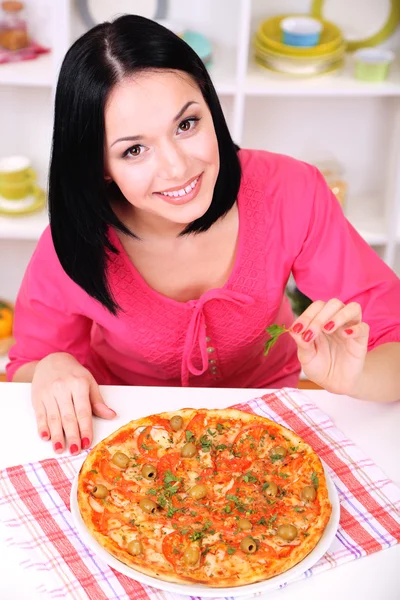 Vacker flicka med läckra pizza på kök bakgrund — Stockfoto