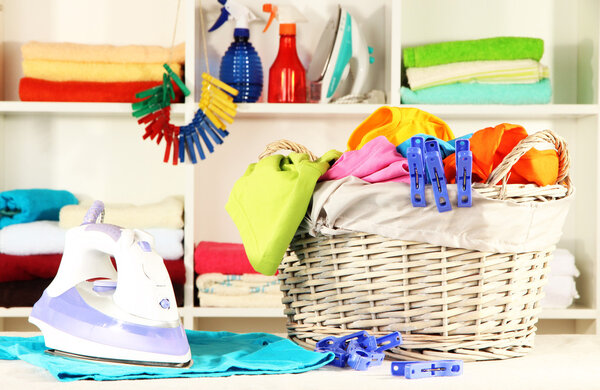 Одежда и утюг на столе на полках
