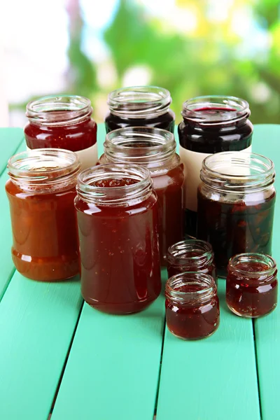 Tasty jam in banks on table on bright background — Stock Photo, Image