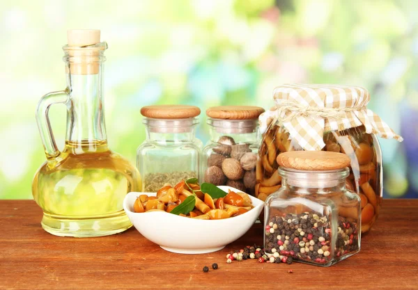 Composition of delicious marinated mushrooms, oil and spices on wooden table on bright background — Stock Photo, Image