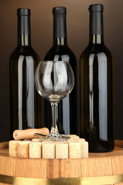 Wine and corks on barrel on brown background — Stock Photo, Image