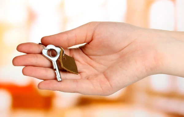 Key with leather trinket in hand on bright background — Stock Photo, Image