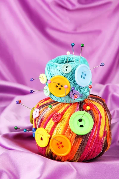Boutons colorés et boules de laine multicolore, sur fond de tissu couleur — Photo
