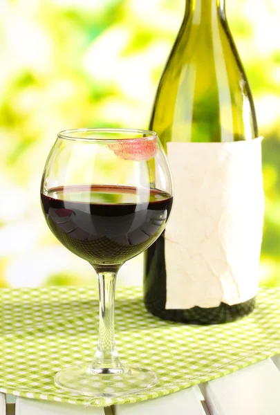 Glass of wine and bottle on table on nature background — Stock Photo, Image