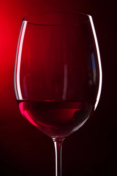 Copo de vinho no fundo vermelho brilhante — Fotografia de Stock