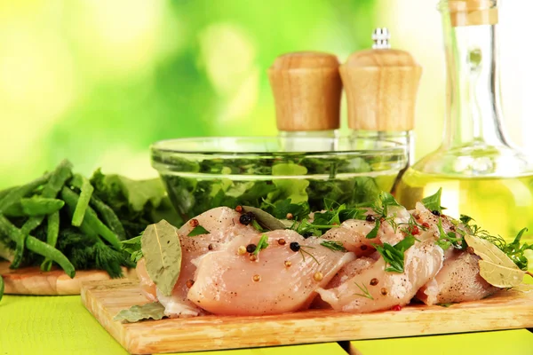 Hühnerfleisch im Glasteller, Kräuter und Gewürze auf dem Tisch vor Naturhintergrund — Stockfoto