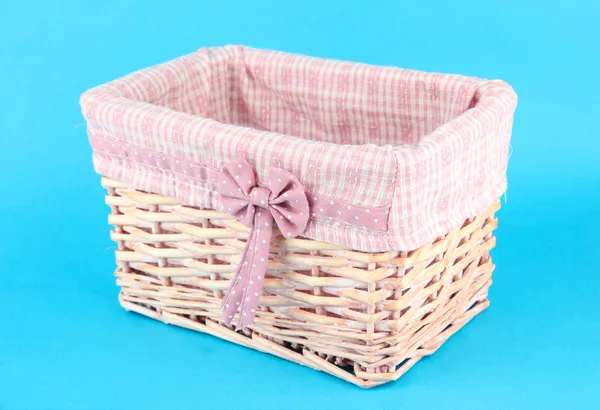 Wicket basket with pink fabric and bow, on color background — Stock Photo, Image