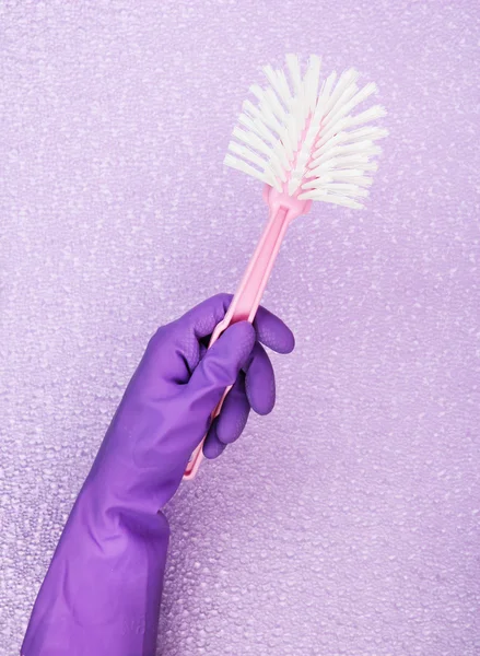 Toilet brush in hand on purple background — Stock Photo, Image