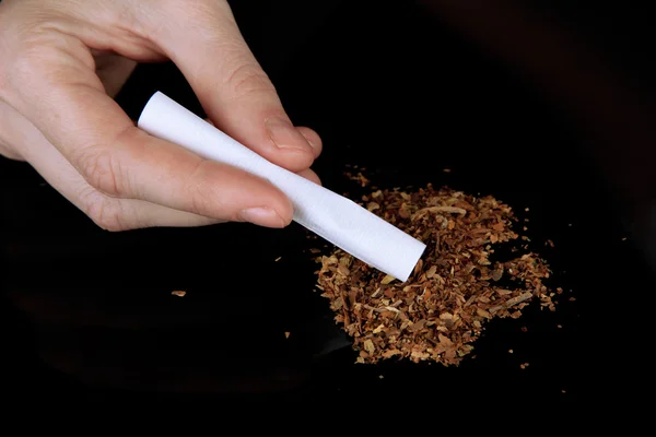 Hands making cigarette isolated on black — Stock Photo, Image