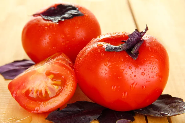 Pomodori freschi e foglie di basilico su fondo di legno — Foto Stock