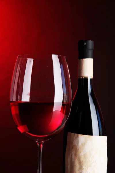 Copa de vino con botella sobre fondo rojo brillante — Foto de Stock